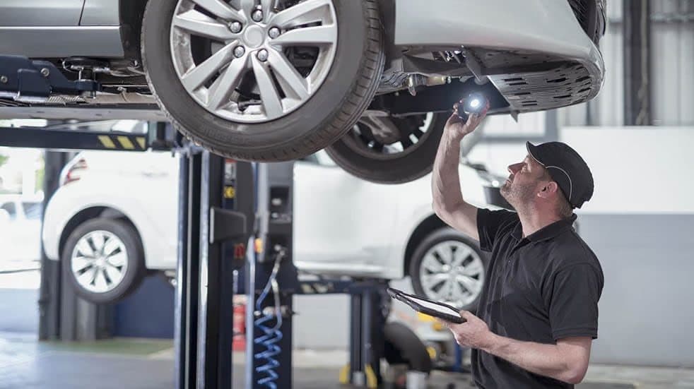 A technician inspecting the underside of an electric vehicle on a lift